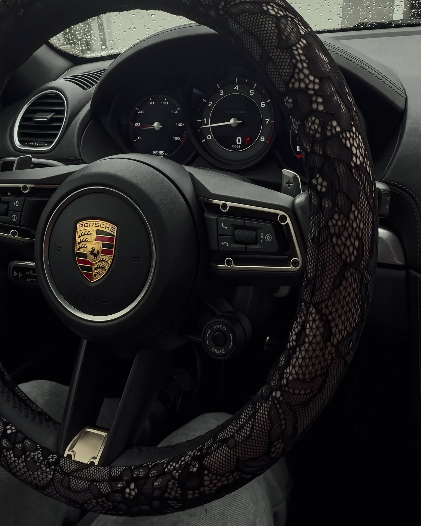 The black lace wheel cover on a Porsche wheel, rain on the windscreen