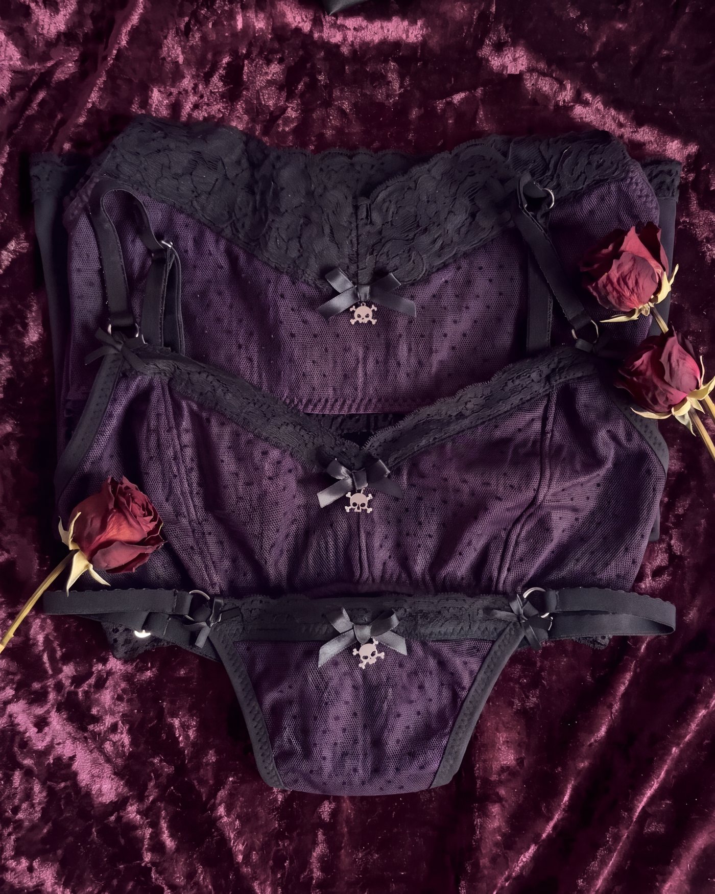 The Mortelle Set in aubergine, stacked on black cherry velvet with dried roses